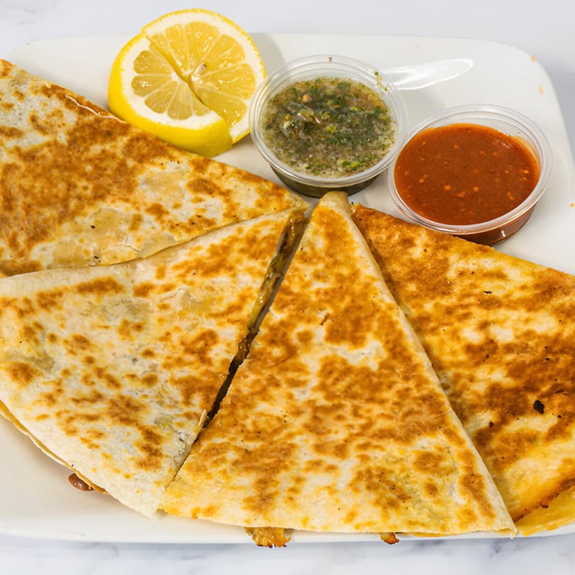 Golden-brown quesadillas, cut into triangles, served with lemon wedges and two dipping sauces.