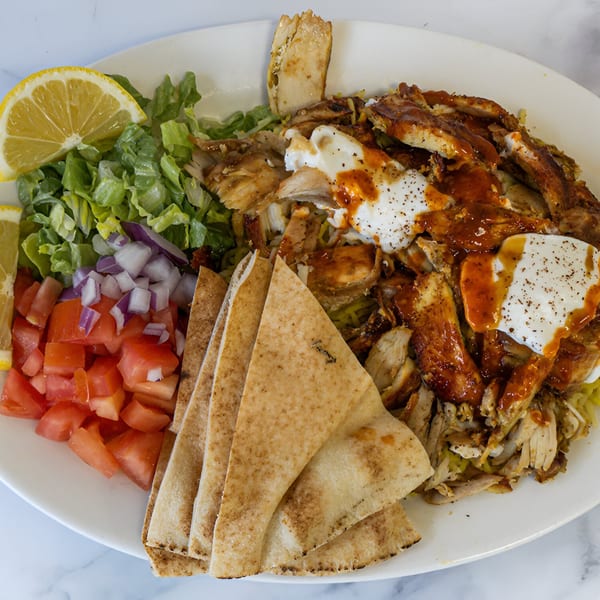 Shawarma Azmi's chicken shawarma plate with pita bread, salad, tomatoes, onions, and lemon.