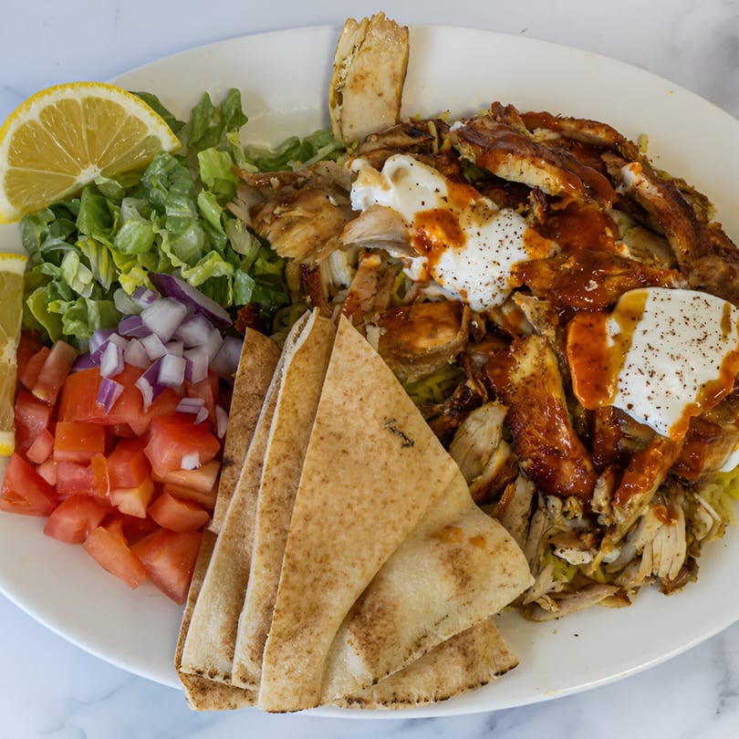 Shawarma Azmi's chicken shawarma plate with pita bread, salad, tomatoes, onions, and lemon.
